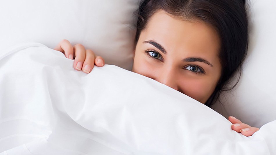 mujer morena debajo de las sábanas