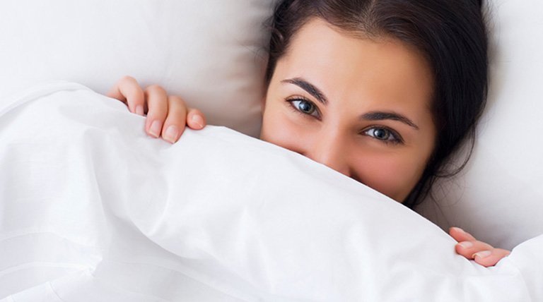mujer morena debajo de las sábanas
