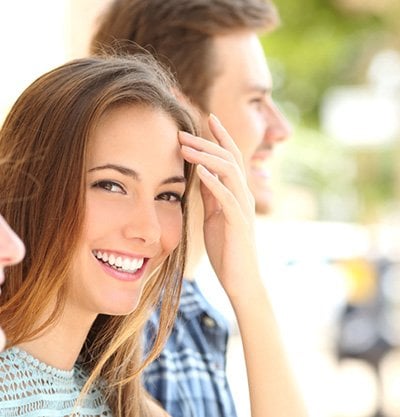 Chica mirando a camara y riendo junto a dos amigos