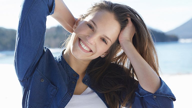 mujer joven sonriendo con el mar de fondo