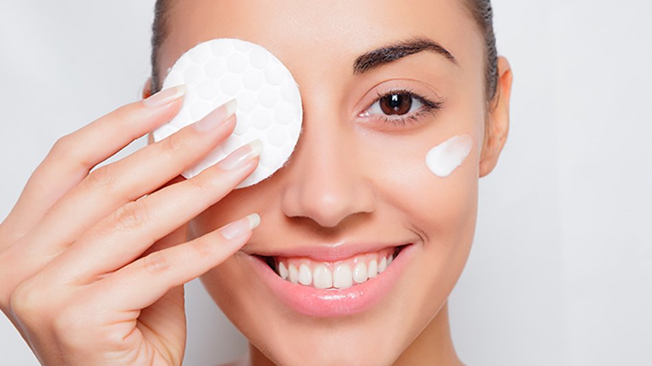 mujer morena sonriendo y desmaquillándose