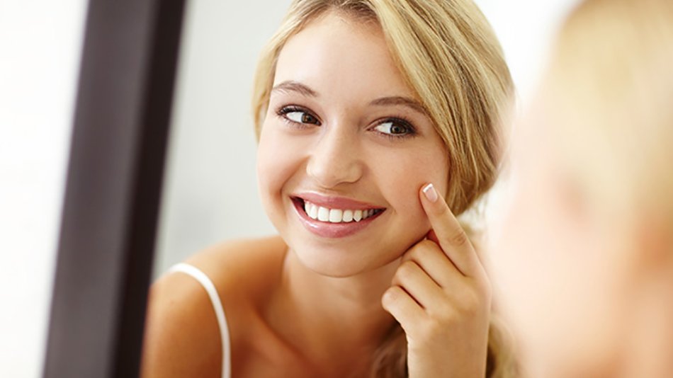 mujer rubia sonriendo frente al espejo