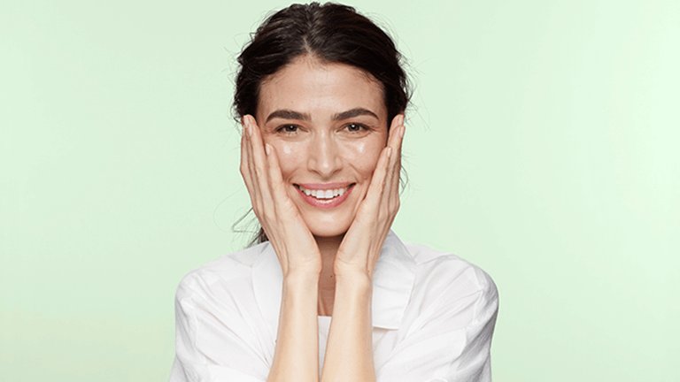 mujer sonriendo tocándose la cara