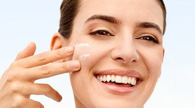 mujer echándose crema en la cara