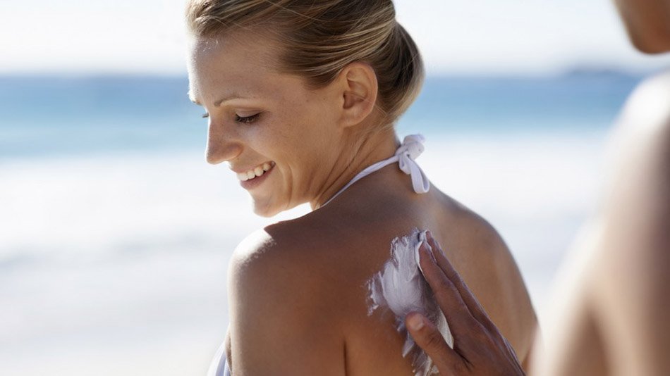 Hombre aplicando crema solar a mujer