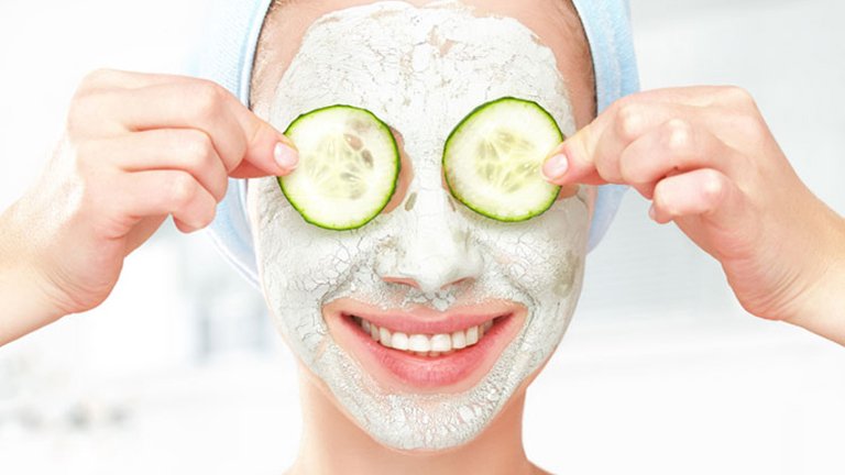 Mujer con mascarilla facial y rodajas de pepino