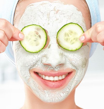 Mujer con mascarilla facial y rodajas de pepino