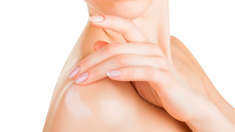 Mujer aplicándose crema en el hombro