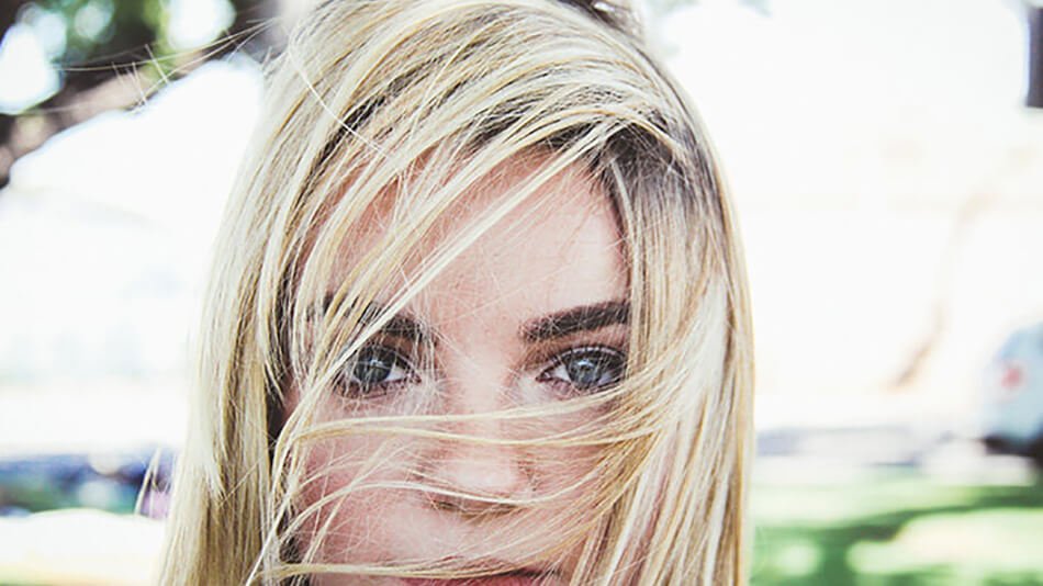 mujer rubia con el cabello en la cara