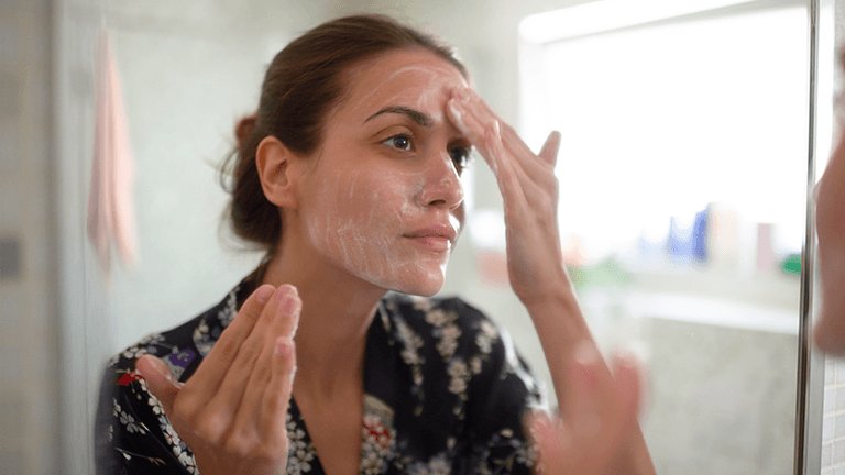 mujer morena mirándose la cara al espejo