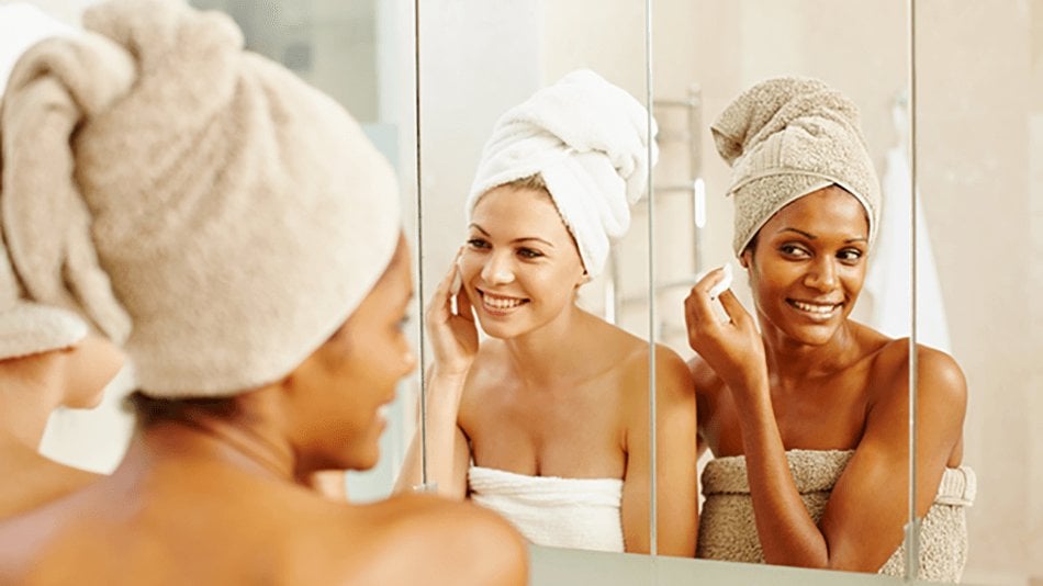 Dos mujeres desmaquillándose frente al espejo