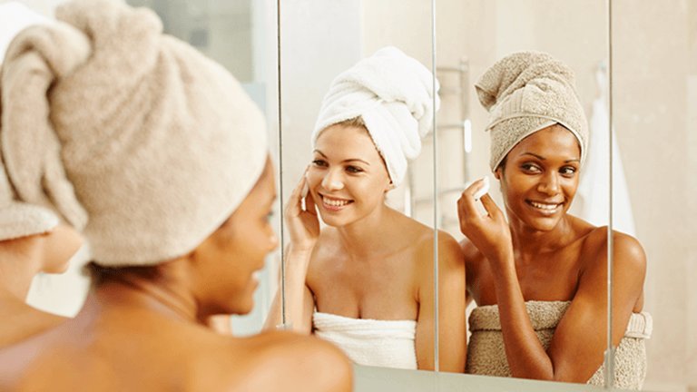 Dos mujeres desmaquillándose frente al espejo