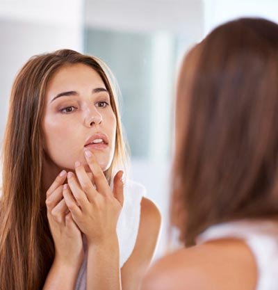 Chica quitandose un grano en el espejo