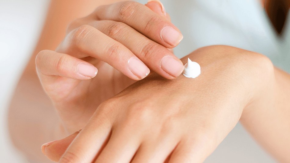 mujer aplicándose crema en las manos