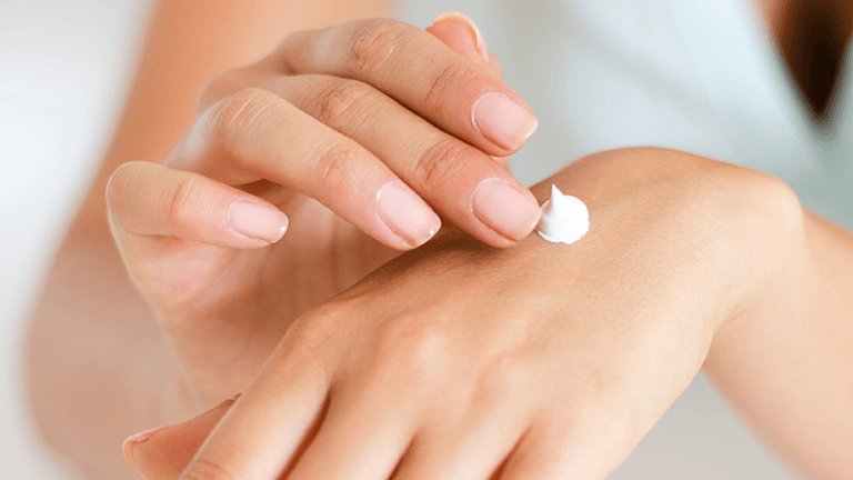mujer aplicándose crema en las manos